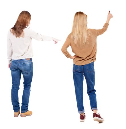 Back view of two pointing young girl in sweater. Rear view people collection. backside view of person. beautiful woman friends showing gesture. Rear view. Isolated over white background.の写真素材