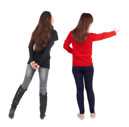 Back view of two pointing young girl in sweater. Rear view people collection. backside view of person. beautiful woman friends showing gesture. Rear view. Isolated over white background.の写真素材