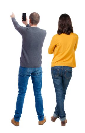 Back view of couple in sweater with mobile phone. beautiful friendly girl and guy together. Rear view people collection. backside view of person. Isolated over white background.の写真素材
