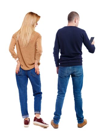Back view of couple in sweater with mobile phone. beautiful friendly girl and guy together. Rear view people collection. backside view of person. Isolated over white background.の写真素材