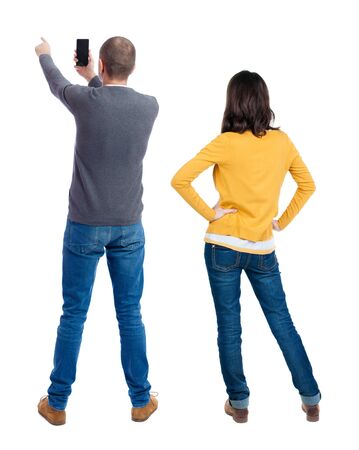 Back view of couple in sweater with mobile phone. beautiful friendly girl and guy together. Rear view people collection. backside view of person. Isolated over white background.の写真素材