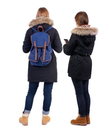 Back view of two young woman photographed on a mobile phone in winter jacket. Rear view people collection. backside view of person. Rear view. Isolated over white background.の写真素材