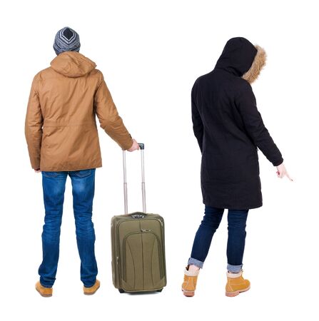 young couple in winter jacket traveling with suitcas. Back view. Rear view people collection. backside view of person. Isolated over white background.の写真素材