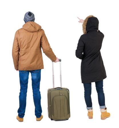 young couple in winter jacket traveling with suitcas. Back view. Rear view people collection. backside view of person. Isolated over white background.の写真素材