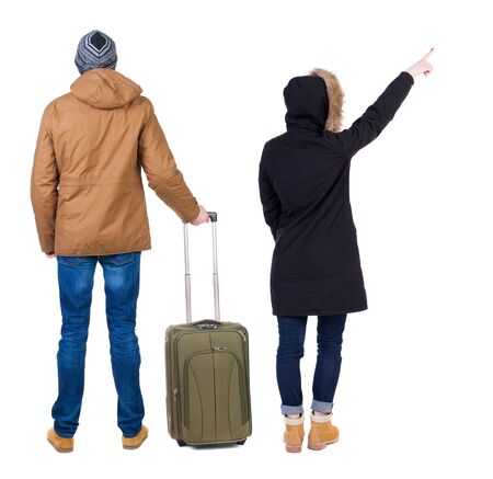 young couple in winter jacket traveling with suitcas. Back view. Rear view people collection. backside view of person. Isolated over white background.の写真素材