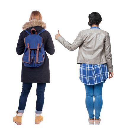 Back view of two young girl in winter jacket showing thumb up. Rear view people collection. backside view of person. beautiful woman friends showing gesture. Rear view. Isolated over white background.の写真素材