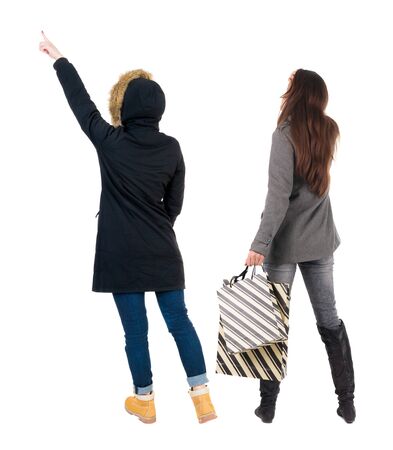 back view of two women with shopping bags in winter jacket. backside view of person. Rear view people collection. Isolated over white background. Two girls with bags stand next procurement.の写真素材