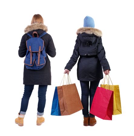 back view of two women with shopping bags in winter jacket. backside view of person. Rear view people collection. Isolated over white background. Two girls with bags stand next procurement.の写真素材