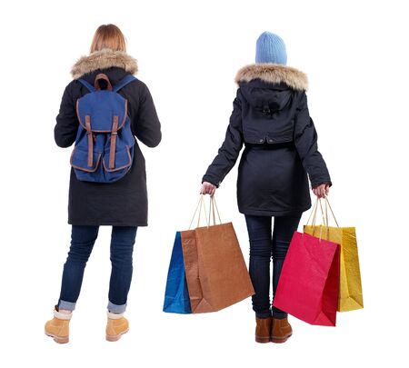 back view of two women with shopping bags in winter jacket. backside view of person. Rear view people collection. Isolated over white background. Two girls with bags stand next procurement.の写真素材