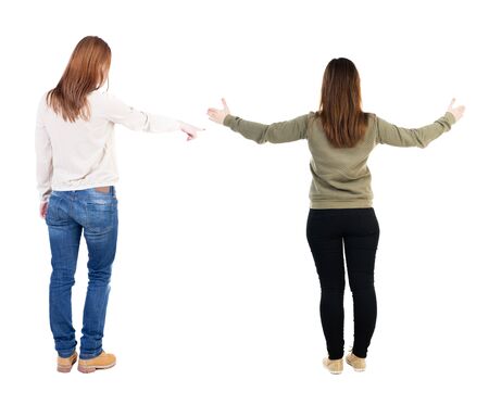 Back view of two pointing girl in sweater. Rear view people collection. backside view of person. beautiful woman showing gesture. Rear view. Isolated over white background.の写真素材