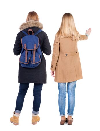 Back view of two pointing girl in winter jacket. Rear view people collection. backside view of person. beautiful woman friends showing gesture. Rear view. Isolated over white background.の写真素材