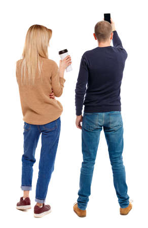 Back view of couple in sweater with mobile phone. beautiful friendly girl and guy together. Rear view people collection. backside view of person. Isolated over white background.の写真素材