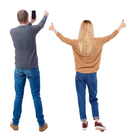 Back view of couple in sweater with mobile phone. beautiful friendly girl and guy together. Rear view people collection. backside view of person. Isolated over white background.の写真素材
