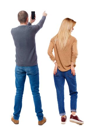 Back view of couple in sweater with mobile phone. beautiful friendly girl and guy together. Rear view people collection. backside view of person. Isolated over white background.の写真素材