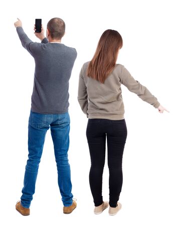 Back view of couple in sweater with mobile phone. beautiful friendly girl and guy together. Rear view people collection. backside view of person. Isolated over white background.の写真素材