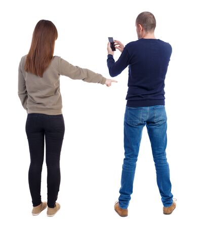 Back view of couple in sweater with mobile phone. beautiful friendly girl and guy together. Rear view people collection. backside view of person. Isolated over white background.の写真素材