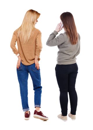 Back view of two young woman photographed on a mobile phone in sweater. Rear view people collection. backside view of person. Rear view. Isolated over white background.の写真素材