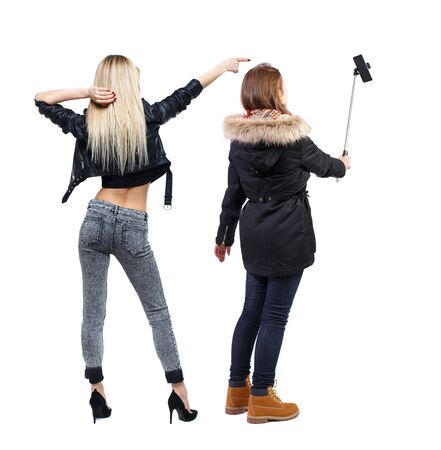 Back view of two young woman photographed on a mobile phone in winter jacket. Rear view people collection. backside view of person. Rear view. Isolated over white background.の写真素材