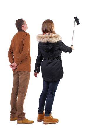 Back view of couple in winter jacket photographed on a mobile phone in winter jacket. beautiful friendly girl and guy together. Rear view people collection. backside view of person. Isolated over white background.の写真素材