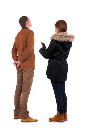 Back view of couple in winter jacket photographed on a mobile phone in winter jacket. beautiful friendly girl and guy together. Rear view people collection. backside view of person. Isolated over white background.の写真素材