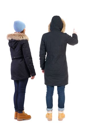 Back view of two pointing girl in winter jacket. Rear view people collection. backside view of person. beautiful woman friends showing gesture. Rear view. Isolated over white background.の写真素材