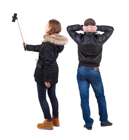 Back view of couple in winter jacket photographed on a mobile phone in winter jacket. beautiful friendly girl and guy together. Rear view people collection. backside view of person. Isolated over white background.の写真素材
