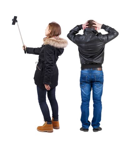 Back view of couple in winter jacket photographed on a mobile phone in winter jacket. beautiful friendly girl and guy together. Rear view people collection. backside view of person. Isolated over white background.の写真素材