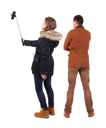 Back view of couple in winter jacket photographed on a mobile phone in winter jacket. beautiful friendly girl and guy together. Rear view people collection. backside view of person. Isolated over white background.の写真素材