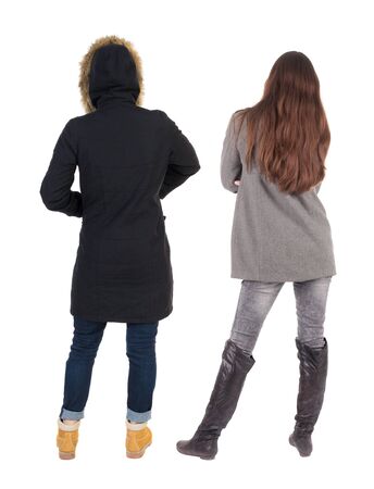 Back view of two young woman in winter jackets. Rear view people collection. backside view of person. Rear view. Isolated over white background. She clung to his girlfriendの写真素材
