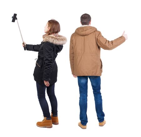 Back view of couple in winter jacket photographed on a mobile phone in winter jacket. beautiful friendly girl and guy together. Rear view people collection. backside view of person. Isolated over white background.の写真素材