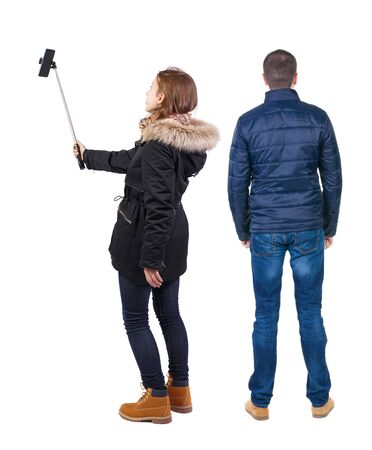 Back view of couple in winter jacket photographed on a mobile phone in winter jacket. beautiful friendly girl and guy together. Rear view people collection. backside view of person. Isolated over white background.の写真素材