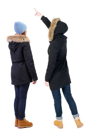 Back view of two pointing girl in winter jacket. Rear view people collection. backside view of person. beautiful woman friends showing gesture. Rear view. Isolated over white background.の写真素材