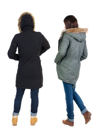 Back view of two young woman in winter jackets. Rear view people collection. backside view of person. Rear view. Isolated over white background. She clung to his girlfriendの写真素材
