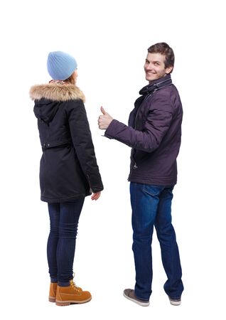 Back view of two young girl in winter jacket showing thumb up. Rear view people collection. backside view of person. beautiful woman friends showing gesture. Rear view. Isolated over white background.の写真素材