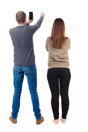 Back view of couple in sweater with mobile phone. beautiful friendly girl and guy together. Rear view people collection. backside view of person. Isolated over white background.の写真素材