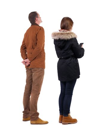 Back view of couple in winter jacket photographed on a mobile phone in winter jacket. beautiful friendly girl and guy together. Rear view people collection. backside view of person. Isolated over white background.の写真素材