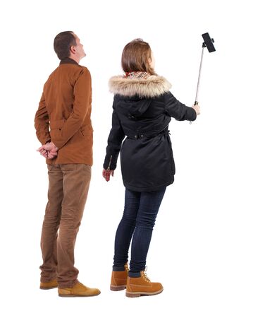Back view of couple in winter jacket photographed on a mobile phone in winter jacket. beautiful friendly girl and guy together. Rear view people collection. backside view of person. Isolated over white background.の写真素材