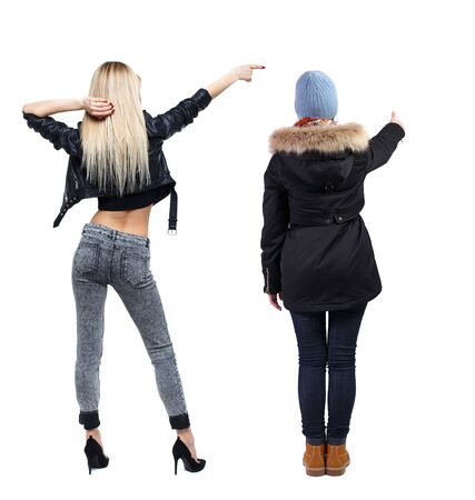 Back view of two pointing young girl in winter jacket. Rear view people collection. backside view of person. beautiful woman friends showing gesture. Rear view. Isolated over white background.の写真素材