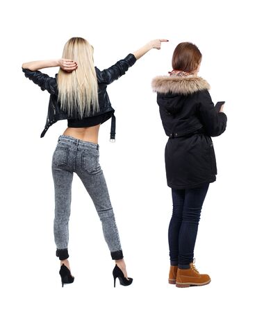 Back view of two young woman photographed on a mobile phone in winter jacket. Rear view people collection. backside view of person. Rear view. Isolated over white background.の写真素材