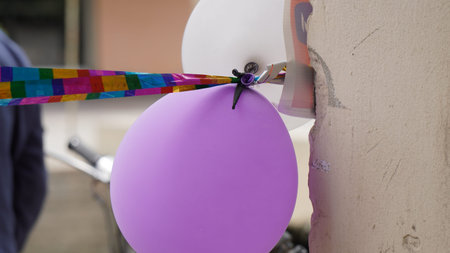 Colorful balloons with ribbons hanging from a wall in the cityの写真素材