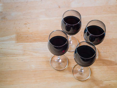 four glasses of red wine on a wooden tableの写真素材