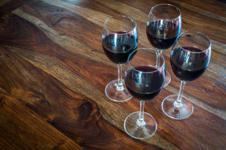 four glasses of red wine on a wooden tableの写真素材