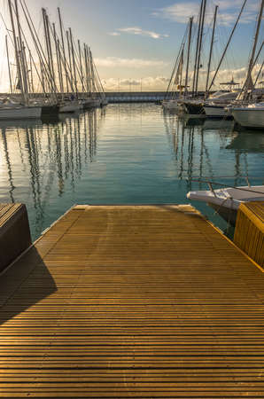 Marina with walkway and boats at sunsetの写真素材