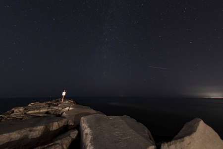 Sea with starry night sky seen from the cliffの写真素材