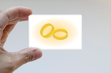 Hand holding card decorated with golden ringsの写真素材