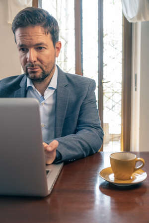 Handsome middle-aged businessman, wearing suit, uses his phone. Isolated. Neutral background.の写真素材