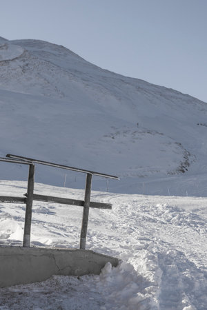 Snowy landscape in the mountains in winter, with a wooden benchの写真素材