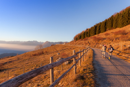 Cansiglio, Veneto, Italy; 2016 - 12 30: young girls walking throughout the sunsetの写真素材