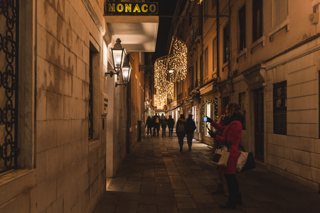 VENICE, ITALY - JANUARY 02 2018: tourists make night photos in a calle. Calle is the typical venetian streetのeditorial素材