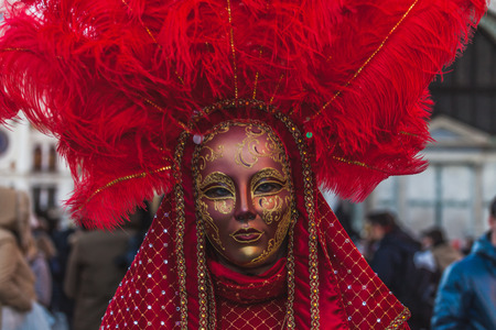 VENICE, ITALY - FEBRUARY 10 2018: Close up of red  dressed carnival mask adorned with fantasy motifs and feathers in San Marco squareのeditorial素材
